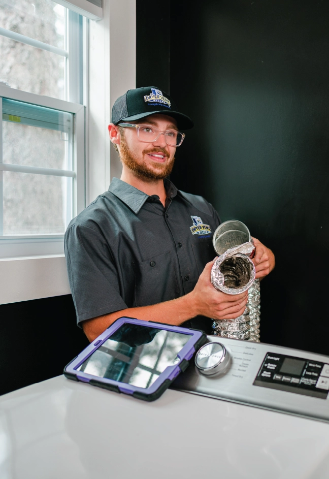 Male dryer vent cleaning professional holds up dirty dryer vent duct and shows female homeowner.